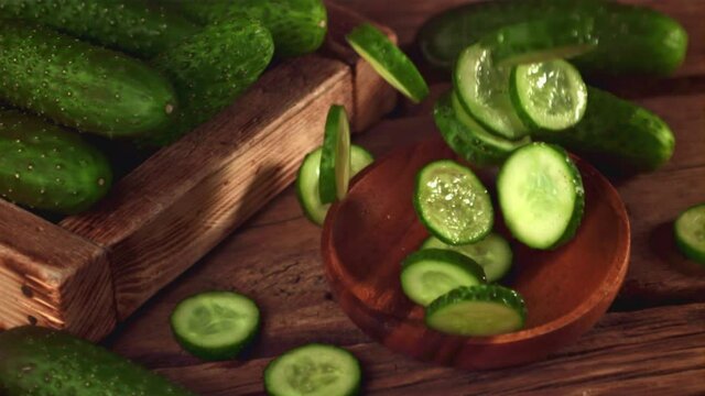 Super slow motion round pieces of cucumber fall into a wooden plate. On a wooden background. Filmed on a high-speed camera at 1000 fps. High quality FullHD footage