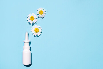Nasal spray and natural chamomiles on a blue background. Treating seasonal allergies. Top view,...