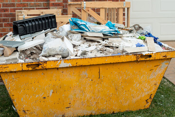 Skip bin full of household waste rubbish on the front yard. House clean up and renovation concept. - obrazy, fototapety, plakaty