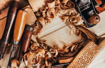 Photo of wooden old fashioned carved planes  laying on workbench table with sawdust upper view.