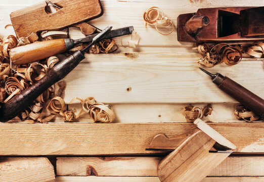 Photo of wooden old fashioned planes with carving chisels laying on workbench table upper view.