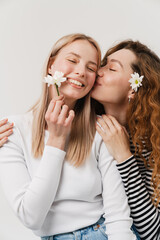 Young white two women kissing while hugging and posing with flowers