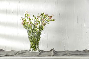 Fresh flowers on white wooden table and wall background with shadow. Free space for your decoration.