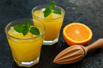 Two glasses of freshly squeezed orange juice on a black background.
Close-up.