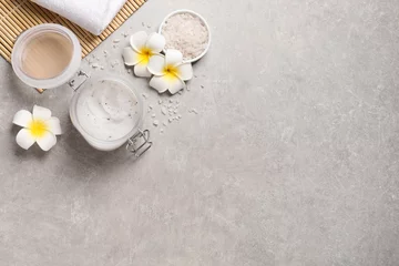 Fototapeten Body scrub, sea salt and plumeria flowers on grey table, flat lay. Space for text © New Africa