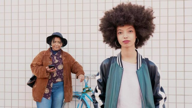 Girlfriends moving to music from smartphone in the street