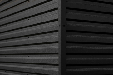 Details of black corrugated iron sheet used as a facade of a warehouse or factory. Texture of a seamless corrugated zinc sheet metal aluminum facade. Architecture. Metal texture.