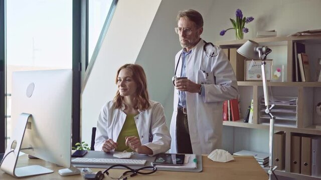 Doctors in practice discussing diagnosis at computer