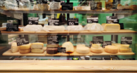 Empty table or counter for your product or text. Table top, mock up. Defocused image of a counter, a department store with farm cheeses, camembert, brie, goat cheese.