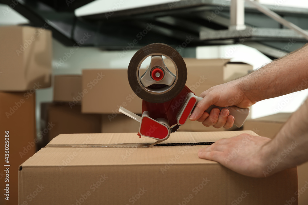 Wall mural worker taping cardboard box indoors, closeup view