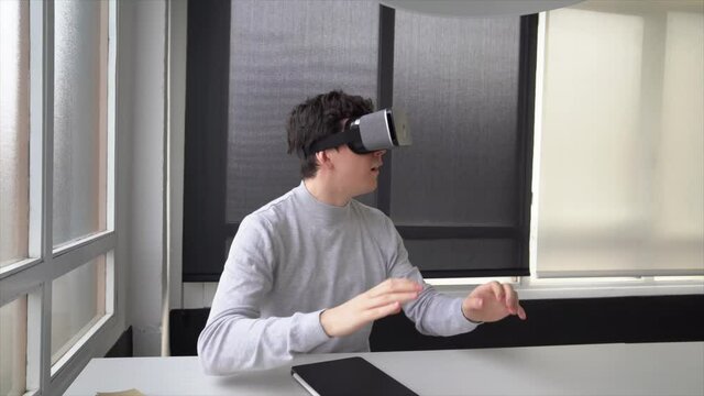 Youn businessman sitting in office using virtual reality simulator