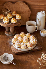 Homemade profiteroles with powdered sugar. Side view, wooden background.