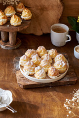 Homemade profiteroles with powdered sugar. Side view, wooden background.