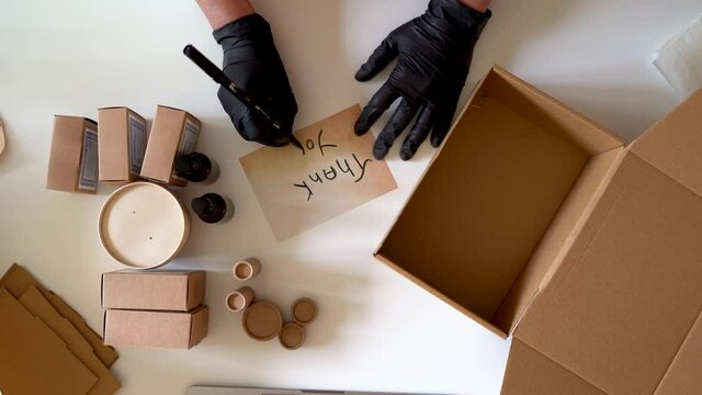 Woman preparing products for shipments writing thank you note