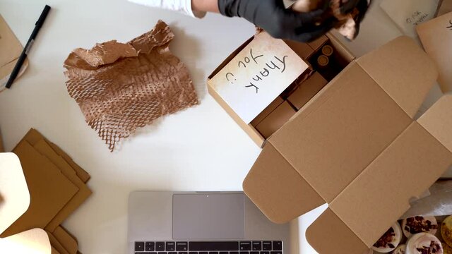 Woman preparing products for shipments writing thank you note