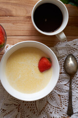 Sweet polenta porrige with strawberries. Top view, wooden background.