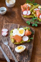Spinach waffles with salmon, egg and radish. Side view, wooden background.