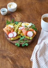 Spinach waffles with salmon, egg and radish. Side view, wooden background.