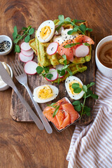 Spinach waffles with salmon, egg and radish. Side view, wooden background.