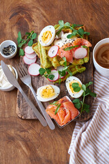Spinach waffles with salmon, egg and radish. Side view, wooden background.