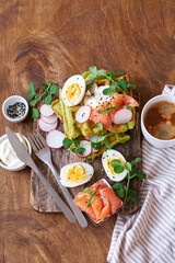 Spinach waffles with salmon, egg and radish. Side view, wooden background.