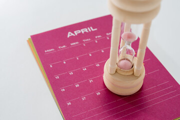 ４月のカレンダーの上に置かれた砂時計のアップ
