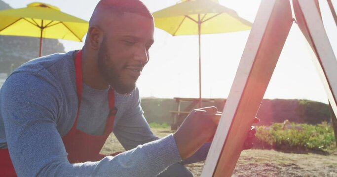 African american man wearing apron writing on food menu slate board of the food truck