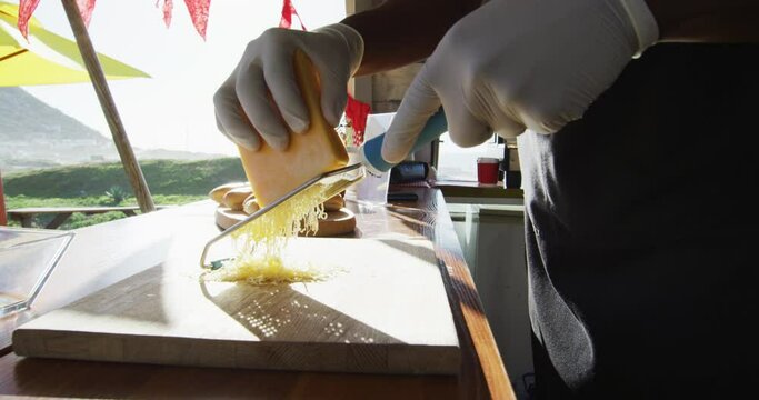 Mid section of african american man wearing gloves grating cheese in the food truck