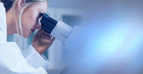 Composition of female lab technician using microscope, with blurred blue copy space to right