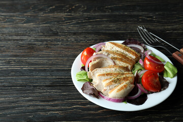 Salad with grilled chicken on wooden table