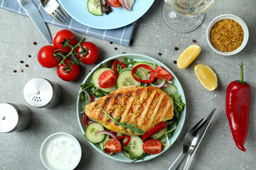 Concept of tasty eating with salad with grilled chicken on gray textured table