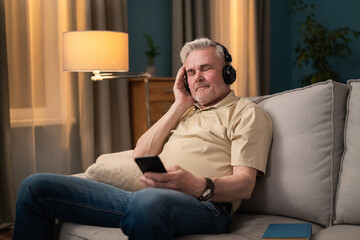 A retiree listens to music on headphones. A senior citizen uses wireless headphones. A man is listening to podcasts on headphones from his phone. An older man listens to his favorite music tracks.