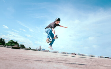 Teenager skateboarder does an ollie trick on background of blue sky gradient