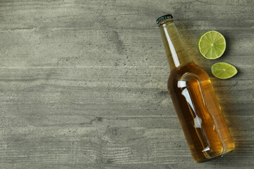 Obraz na płótnie Canvas Bottle of beer and lime on gray textured background
