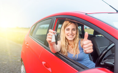 A beautiful woman in a car holds a car key in her hands. Happy young woman in the car.