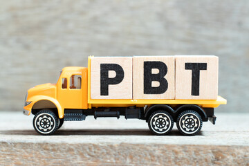 Toy truck hold alphabet letter block in word PBT (Abbreviation of Profit before tax) on wood...