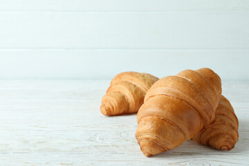 Croissants on white wooden background, space for text