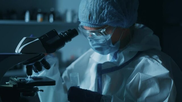 Female scientist is looking through a microscope in laboratory and using microscope for bacterial contamination of water to search for vaccine to treat diseases in medicine.