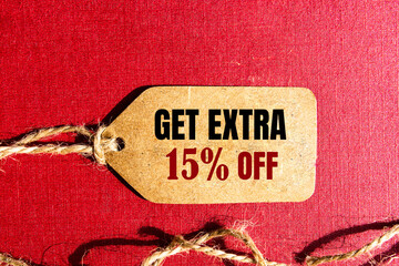 GET EXTRA 15 OFF percent text on a brown tag on a red paper background