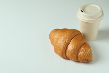 Croissant and paper cup on light gray background