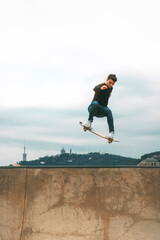 skater jumping high in the air with a snakeboard in a skatepark with white sky in the background with copyspace