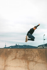 skater jumping high in the air with a snakeboard in a skatepark with white sky in the background with copyspace