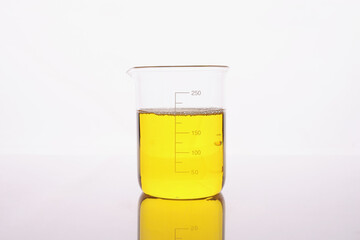 Clear yellow liquid is poured into beaker - obrazy, fototapety, plakaty