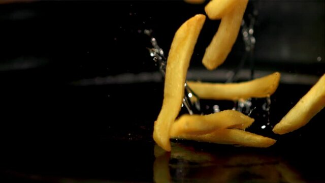 Super slow motion on a hot frying pan drops french fries. On a black background. Filmed on a high-speed camera at 1000 fps.
