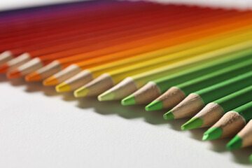 Multi-colored pencils of green-yellow-red shades lie on table