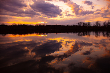 Purple sky clouds with lake reflections at sunset in Michigan, USA.