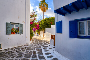Beautiful traditional streets of Greek island towns. Whitewashed houses, bougainvillea in blossom, flower pots, cobblestone pavement. Mykonos, Greece