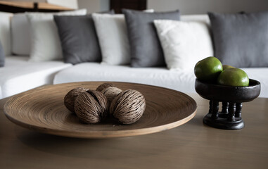 Dry Cerbera Odollam or Pong Pong seed on a wooden plate and orange fruits in a bowl in the living...