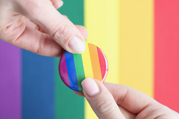 Two people hold lgbt sign against background of flag of sexual minorities