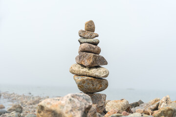 Stack or pile of stones cairn on foggy beach. Balance and harmony concept